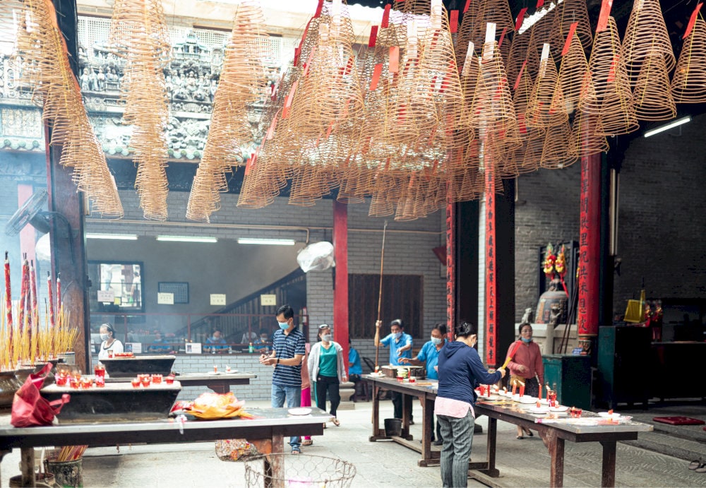 Small groups of worshippers carefully arrange fruits, cakes, and incense on offering trays